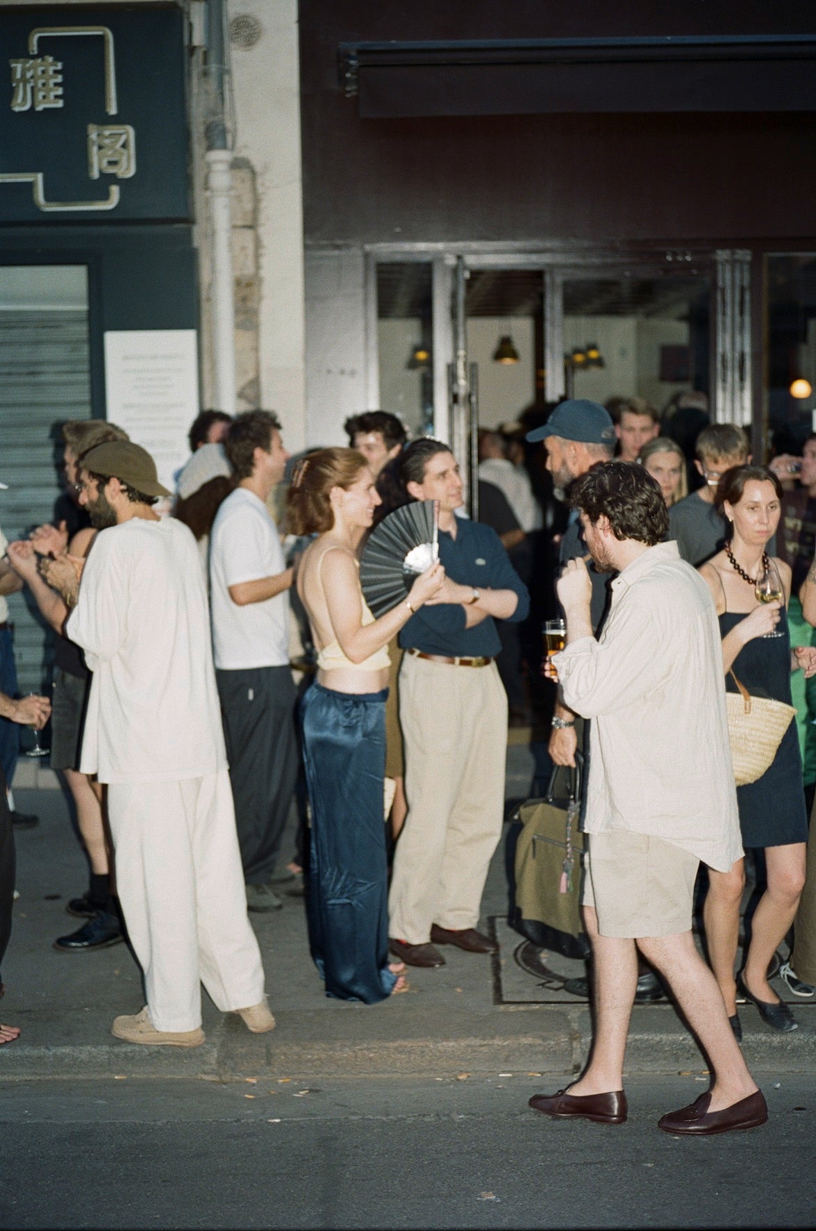 Friends spilling onto the sidewalk at a Colbo party in Paris