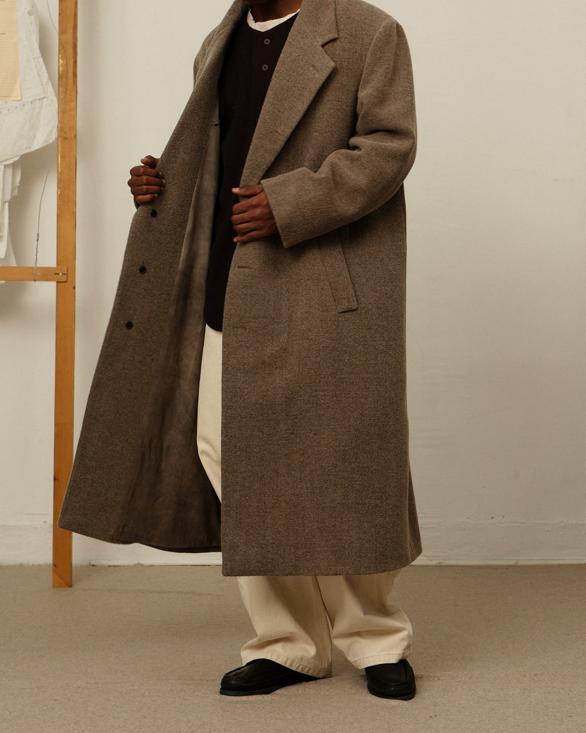 Model wearing suit overcoat in brown.