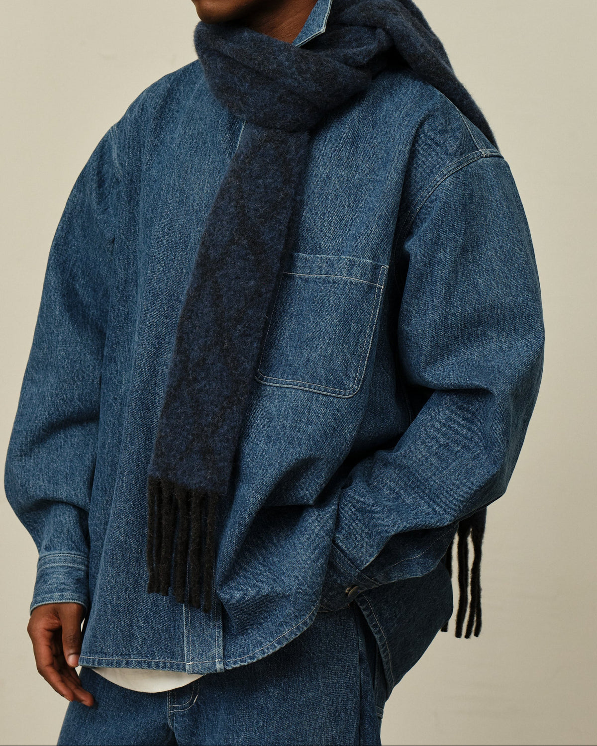 A model wears the Blue Block Scarf
draped around neck over a denim set.
