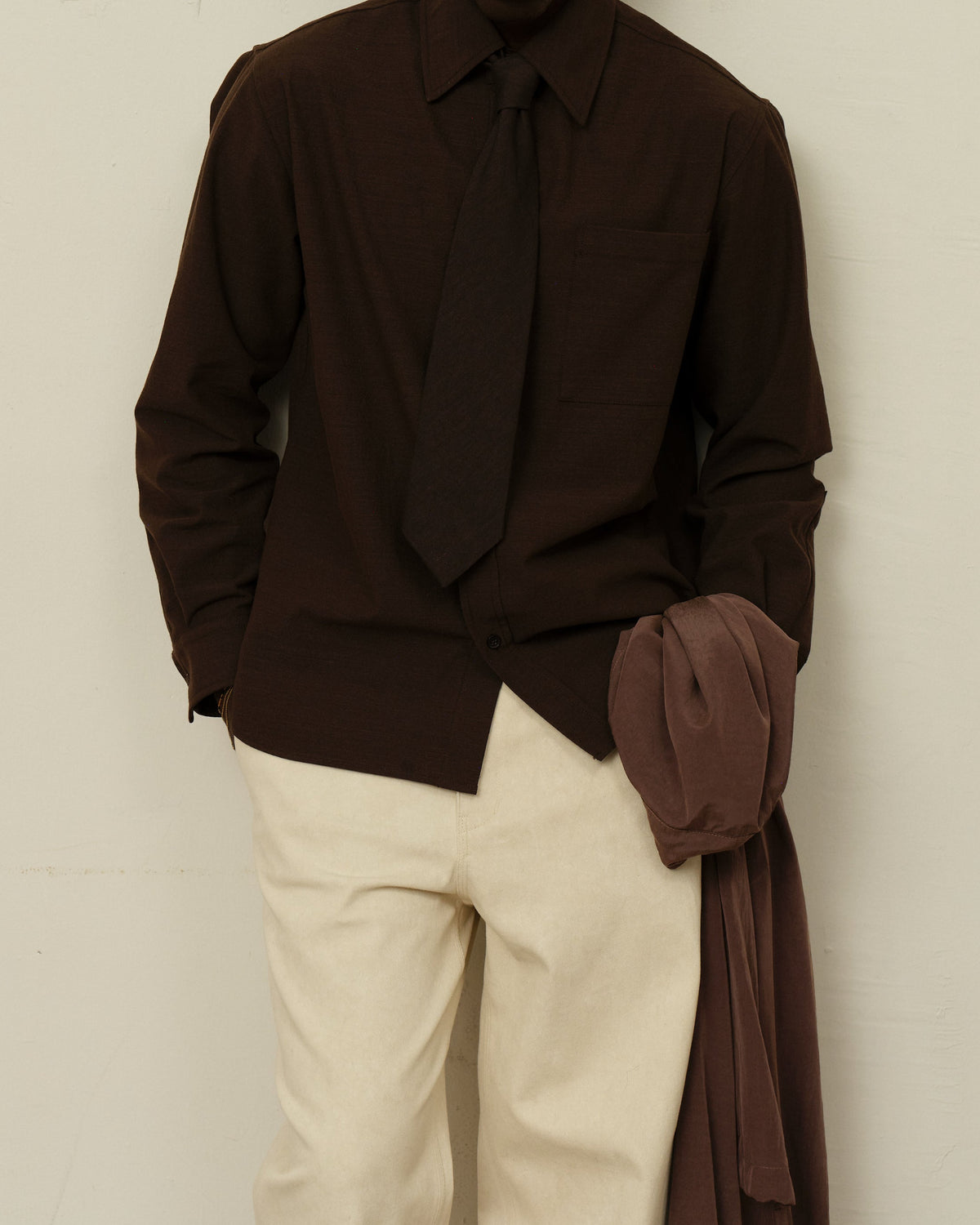A model wears a Tie in Soft Dark Brown over a matching brown shirt with cream pants.