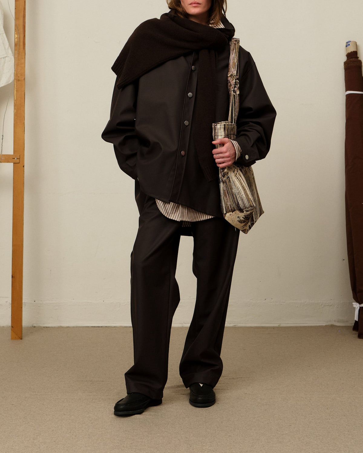 Colbo Chinos in coated deep purple on model, full length, with a dark jacket, scarf and striped shirt