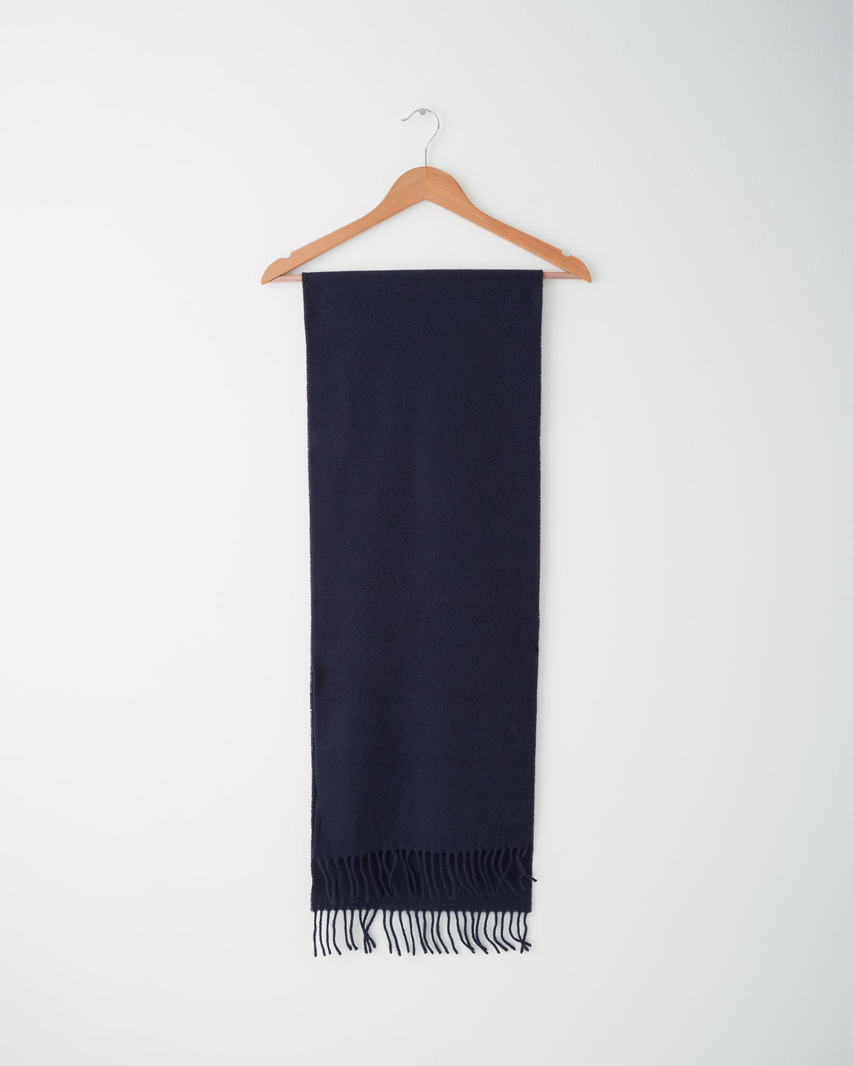 Another Aspect Scarf 1.0 in navy wool-cashmere, folded over a hanger with fringed ends