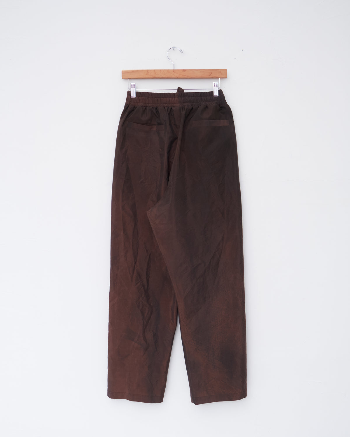 Colbo Draw Pants in washed burgundy Italian fabric, back, on a hanger