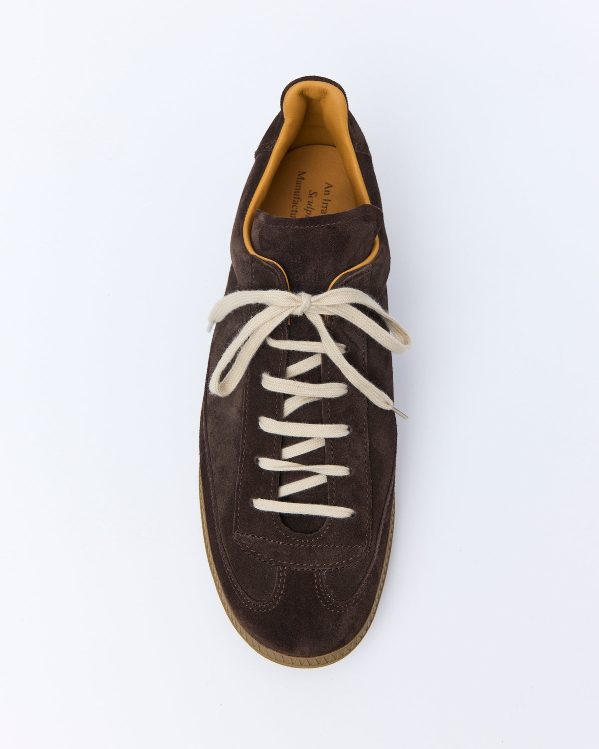 An Irrational Element Sculpture Trainer in chocolate suede, three-quarter back view, shown with cream laces
