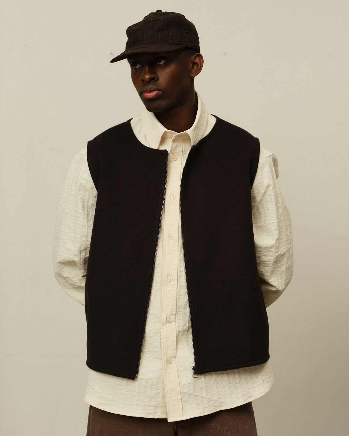 A dark zip vest and textured cream shirt over Colbo Big Pocket Denim in Brown Denim