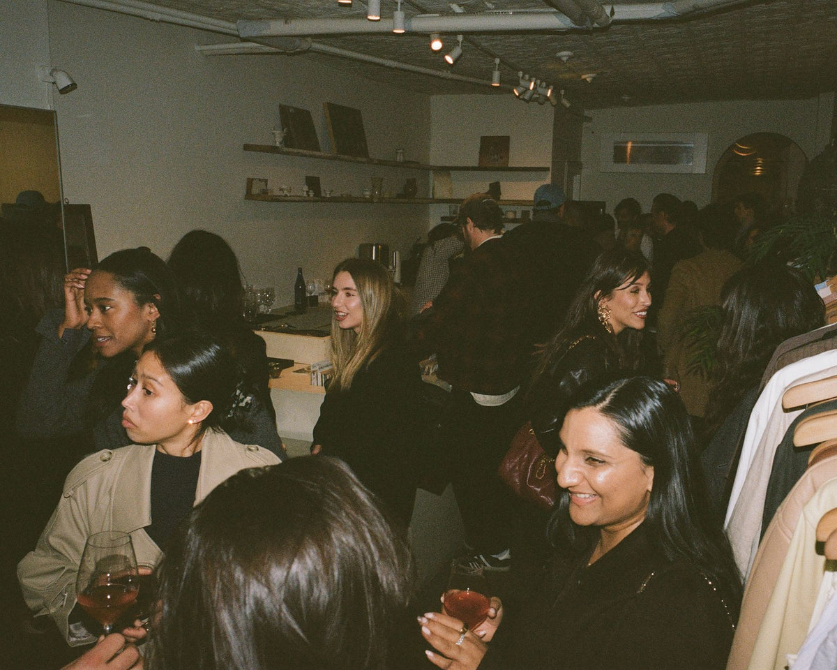 A crowded shop floor at a Colbo party, glasses of wine in hand
