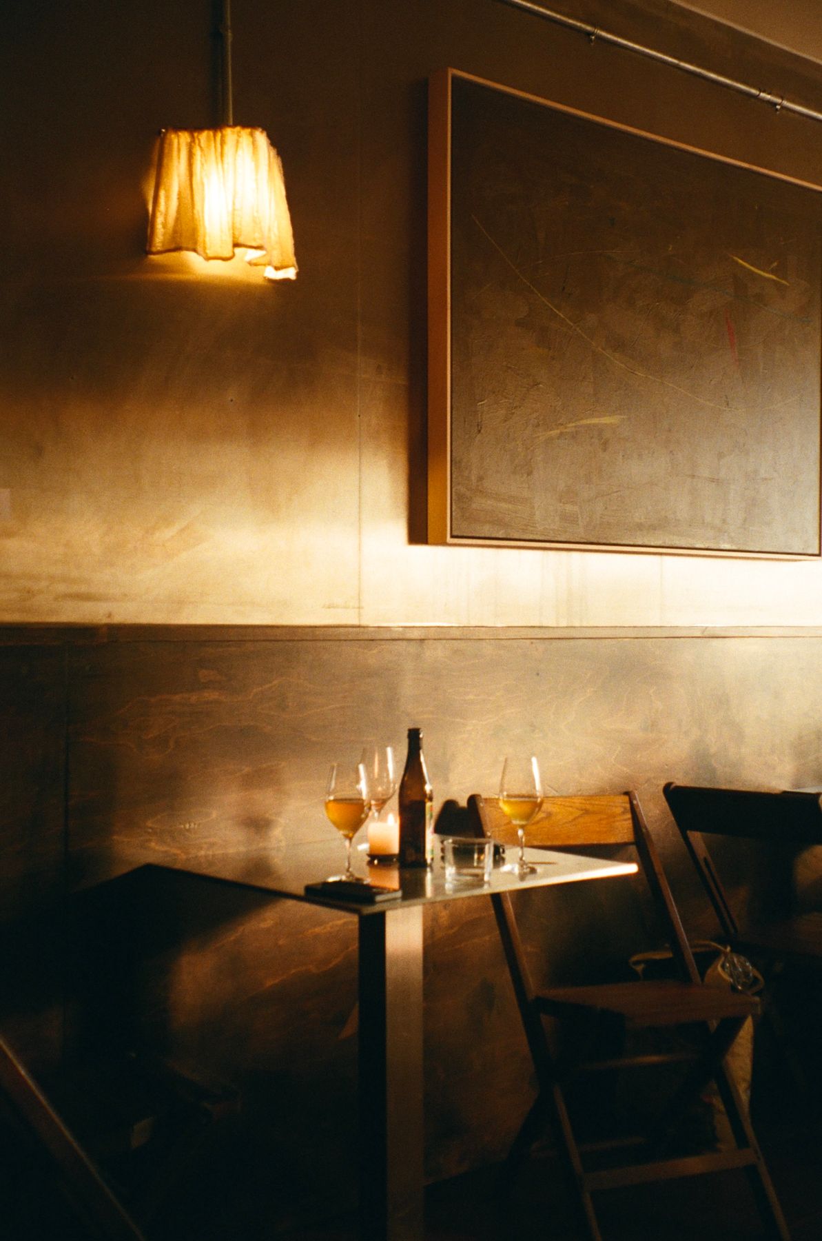 A paper lamp over a table set with wine and a candle at Next Door