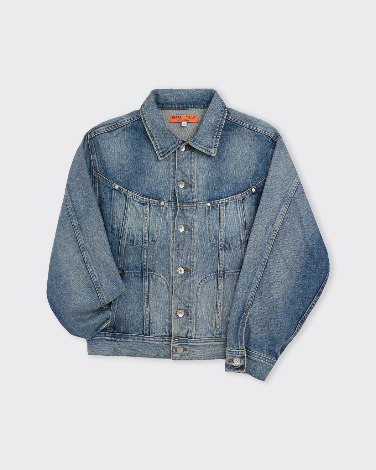 Small Talk Studio Twist Trucker Jacket in washed indigo, three-quarter view