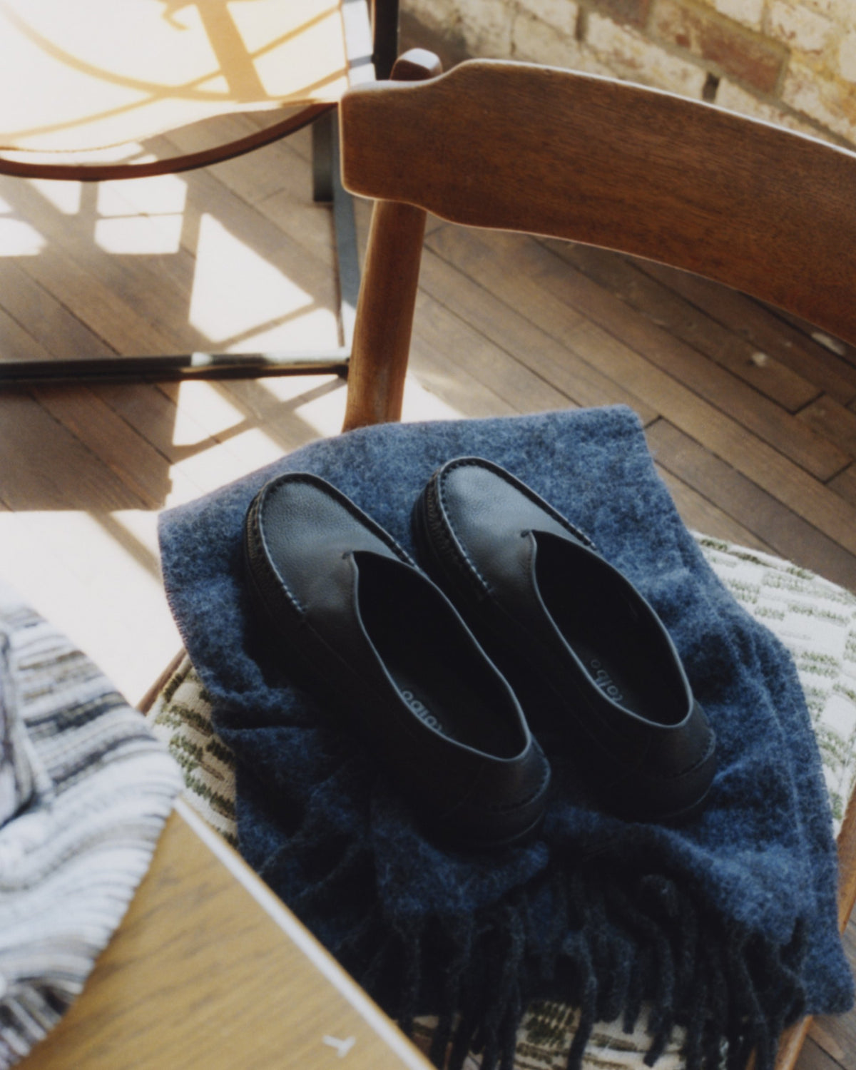 Black Sirah loafers on a navy blanket over a wooden chair