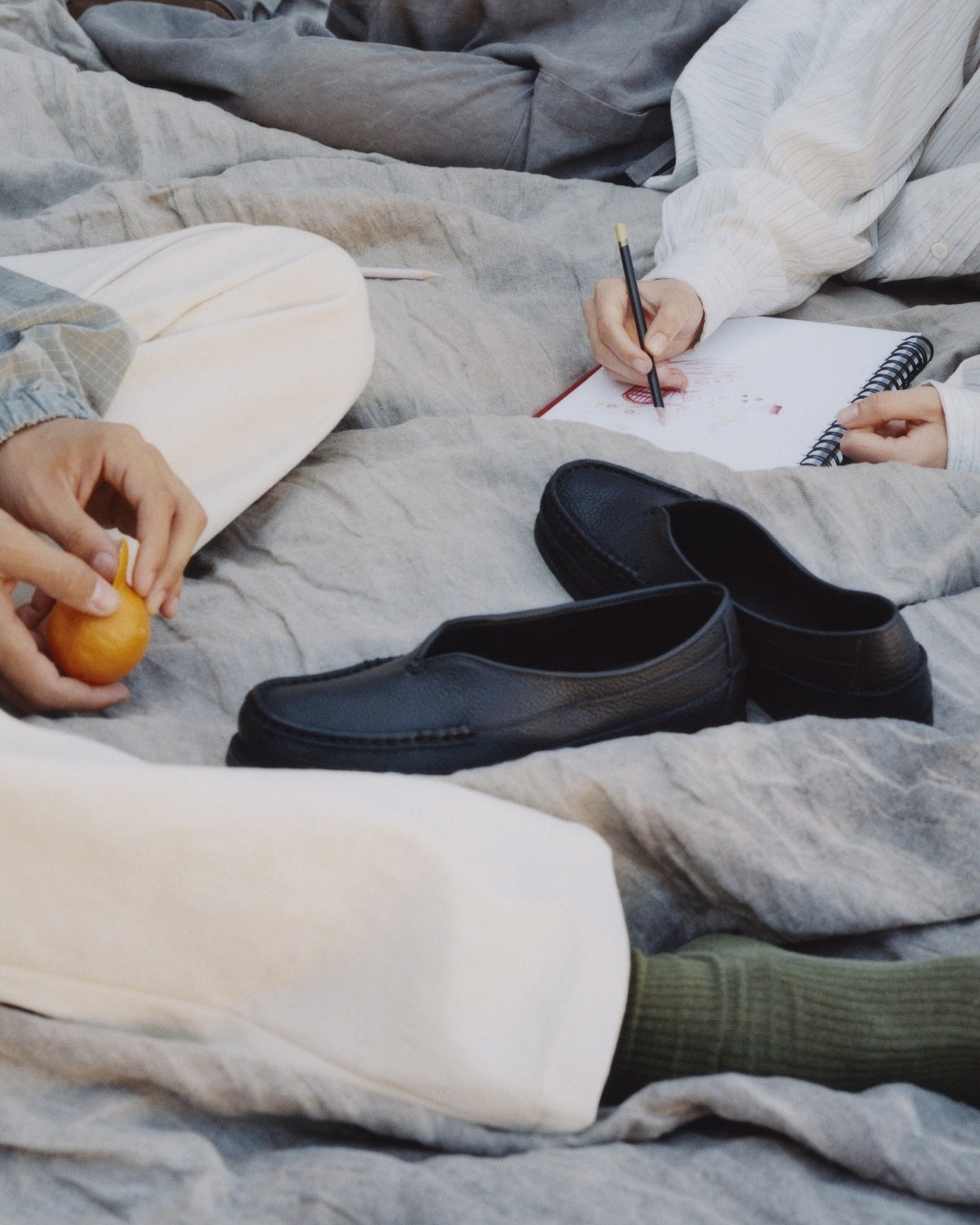 Black Sirah loafers on a gray linen blanket in the grass