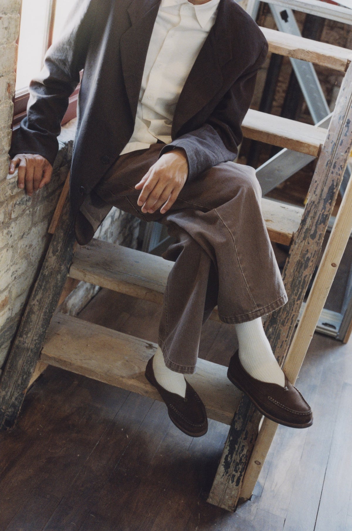 Chocolate Sirah loafers with white socks on an old wooden ladder