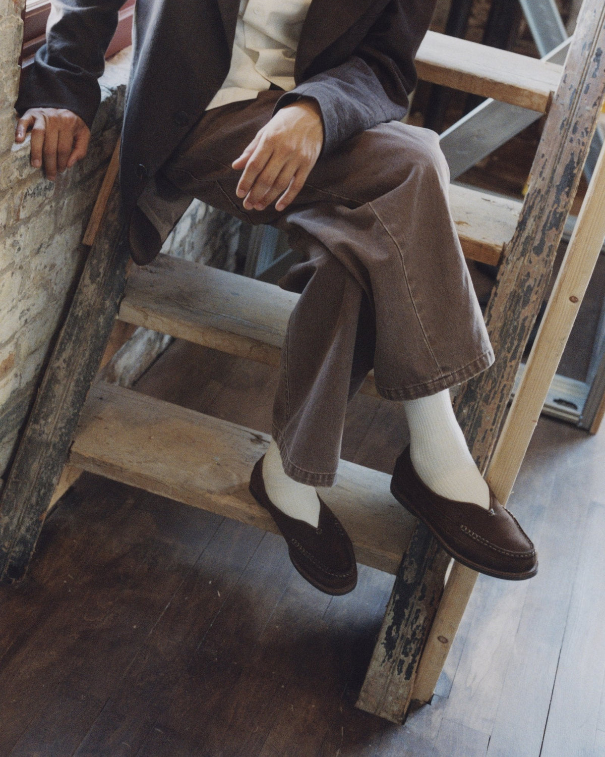 Chocolate Sirah loafers with white socks on an old wooden stair